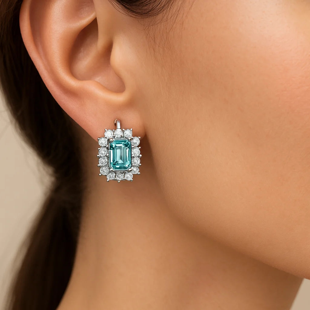 Close-up of a woman wearing a turquoise gemstone earring with a beige background