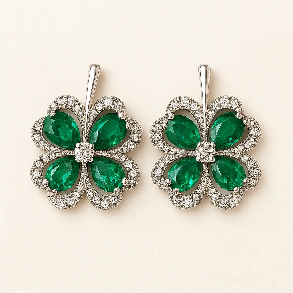 Pair of emerald green four-leaf clover earrings with silver accents on a beige background