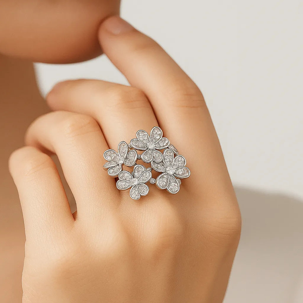 Silver floral ring on a hand against a neutral background
