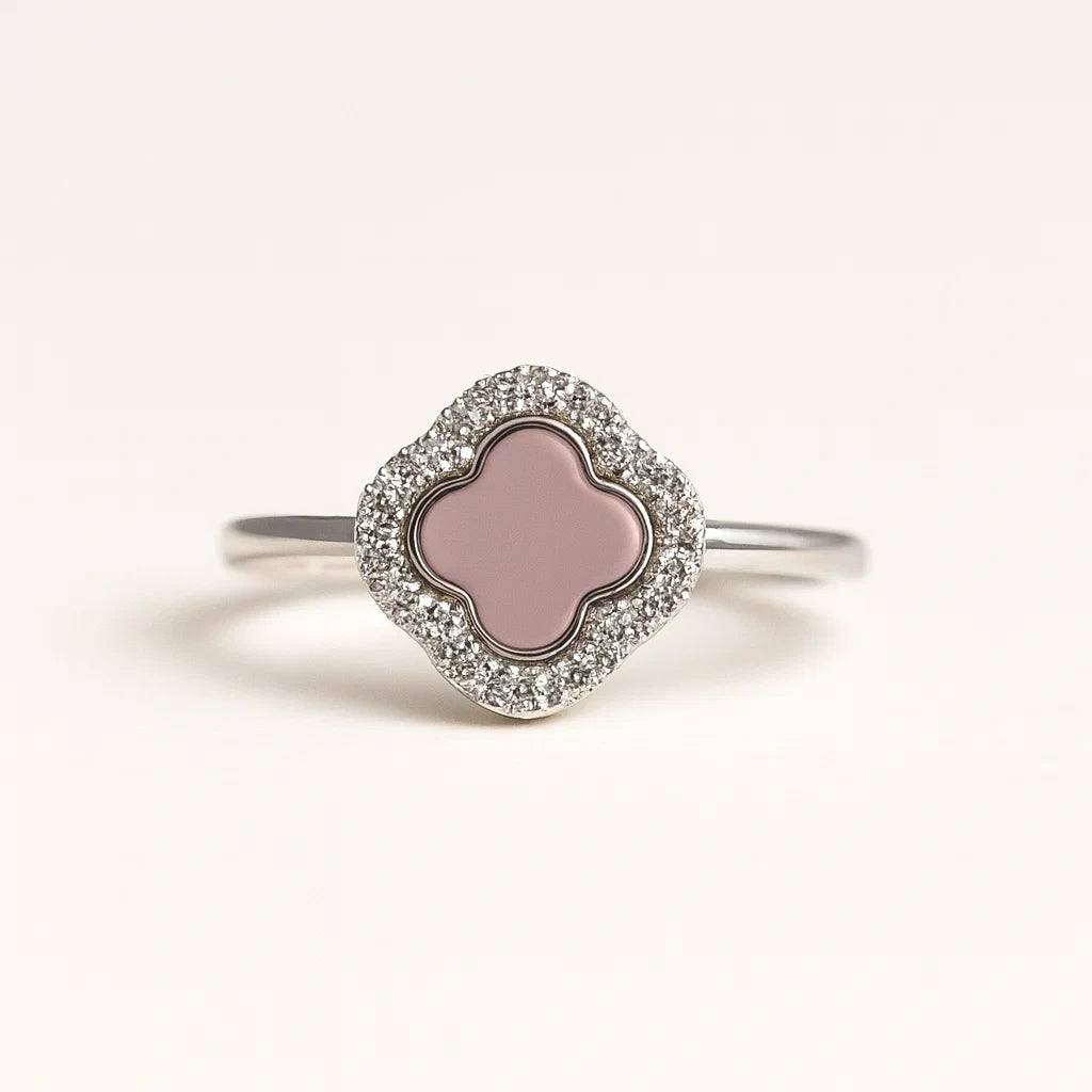 Silver ring with a pink clover-shaped center on a light gray background
