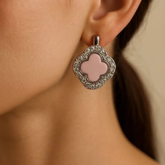 Close-up of a pink clover-shaped earring with a silver frame worn by a person.