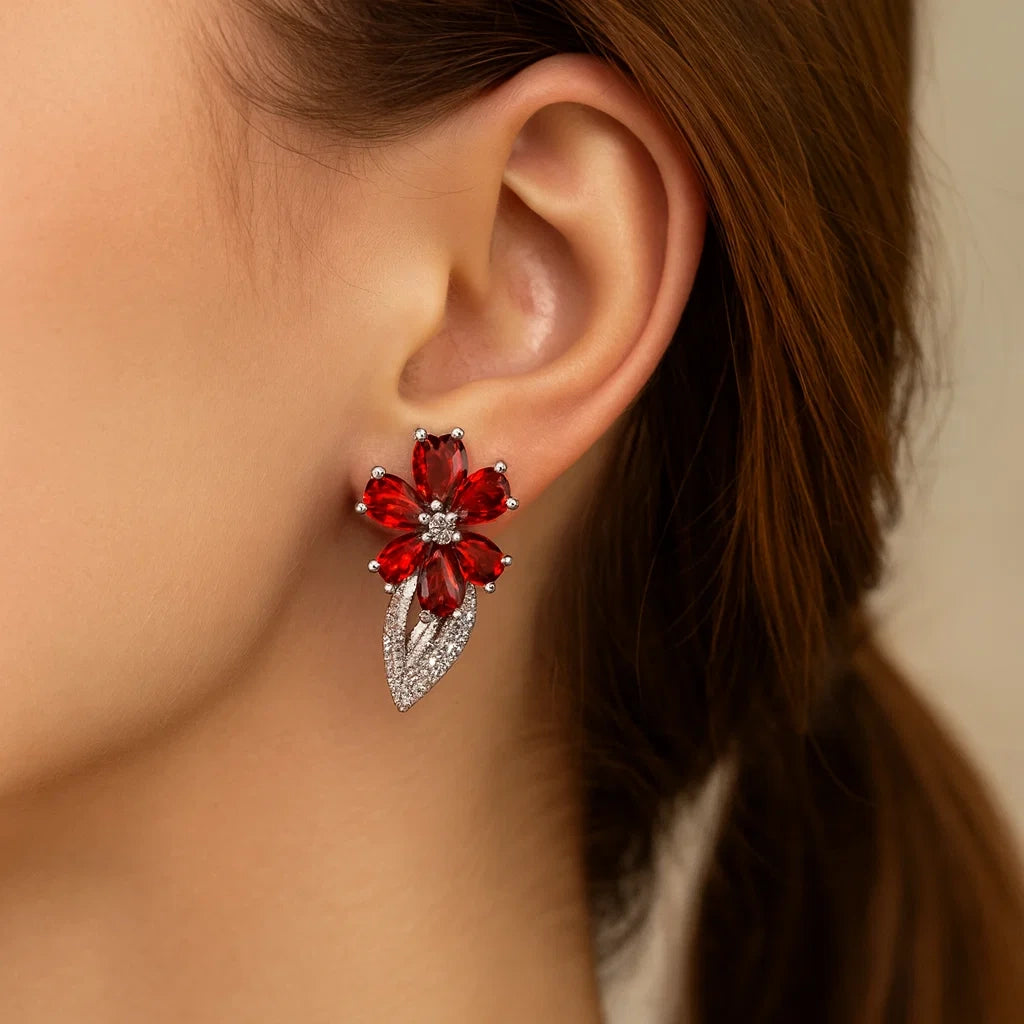 Close-up of a woman's ear wearing a red floral earring with a blurred background