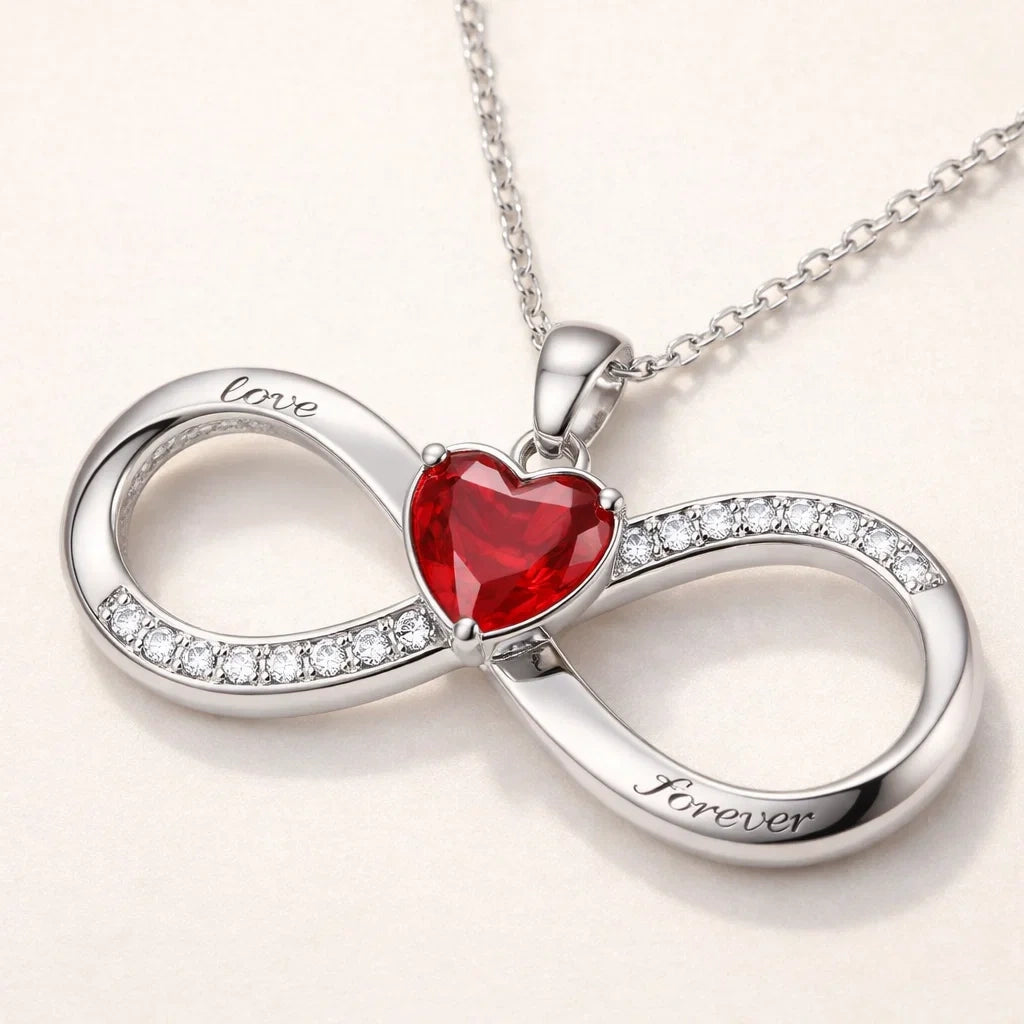 Silver infinity necklace with a red heart and 'love' and 'forever' engravings on a light background
