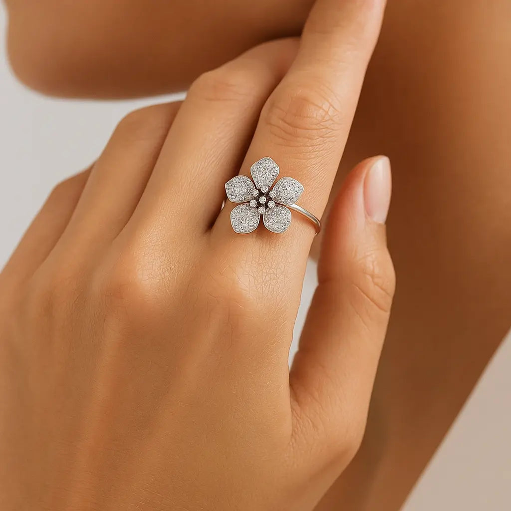 Silver flower-shaped ring on a person's finger with a neutral background