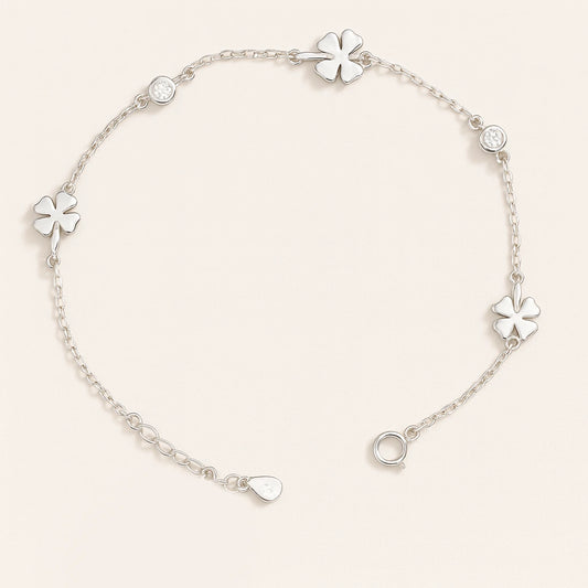 Silver bracelet with clover-shaped charms on a light pink background