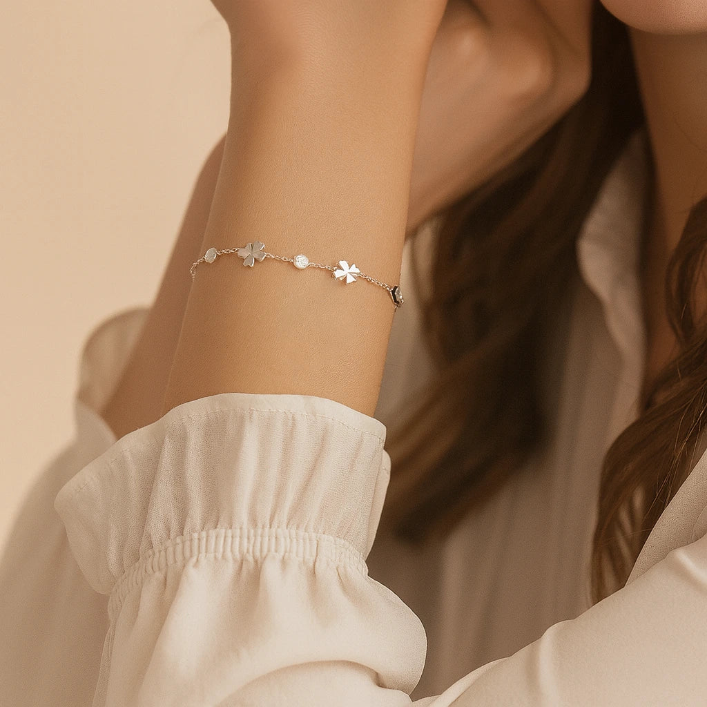Close-up of a person wearing a delicate bracelet with small floral charms on a neutral background