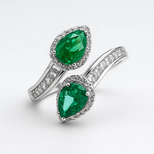 Pair of emerald and diamond rings on a white background