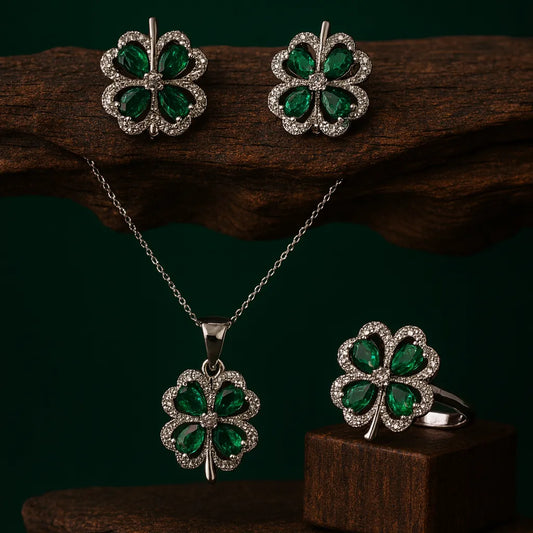 Four-leaf clover jewelry set with earrings, necklace, and ring on a dark background