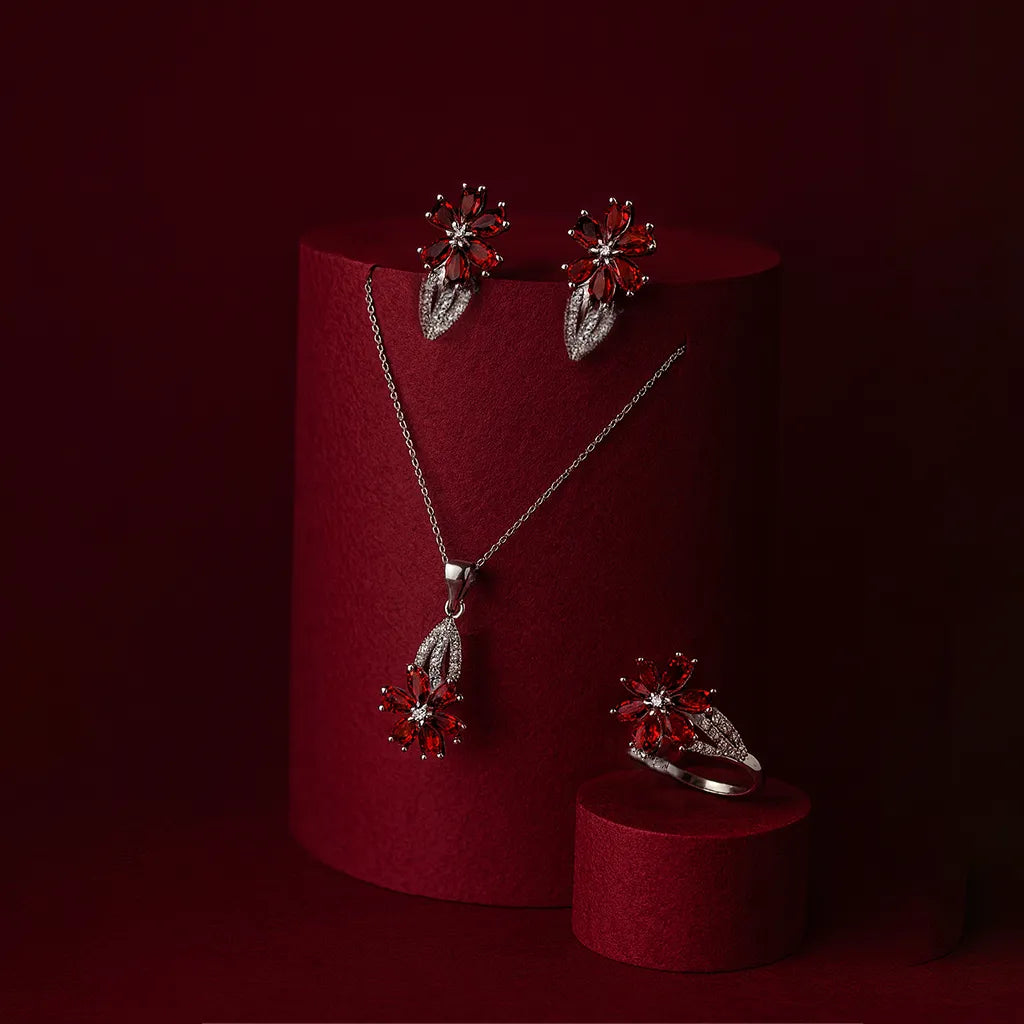 Women's 925 silver ruby red Zircon jewelry set from UAE brand. Includes a ring, stud earrings, and necklace pendant, all featuring a central floral motif with marquise red Zircon and a white Zircon border.