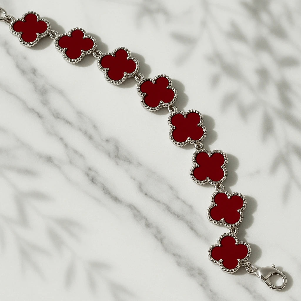 Bracelet with red clover-shaped charms on a marble surface