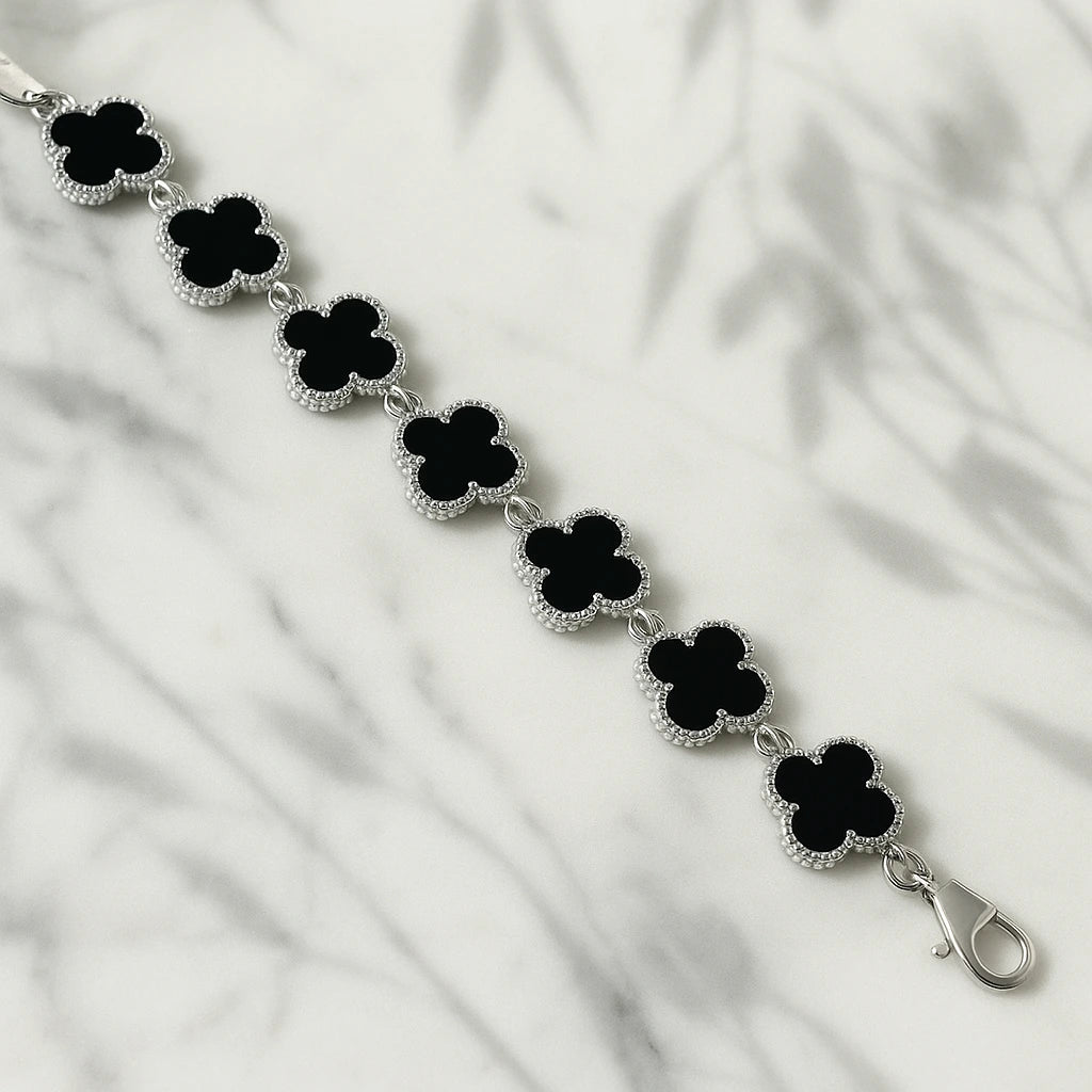 Black clover-shaped bracelet on a white fabric background