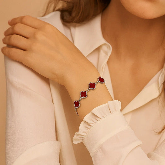 Close-up of a bracelet with red stones on a person's wrist, wearing a light-colored shirt.