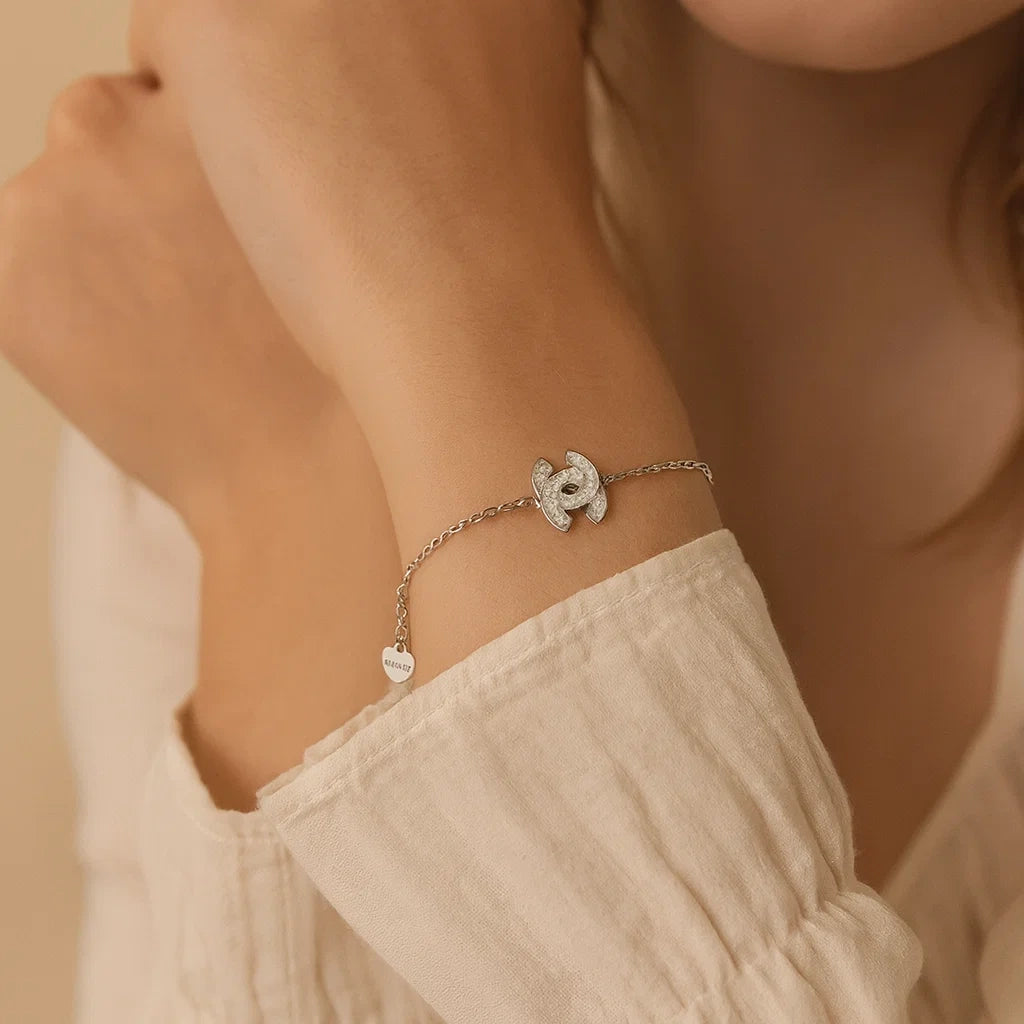 Close-up of a person wearing a delicate silver bracelet with heart charms on a neutral background