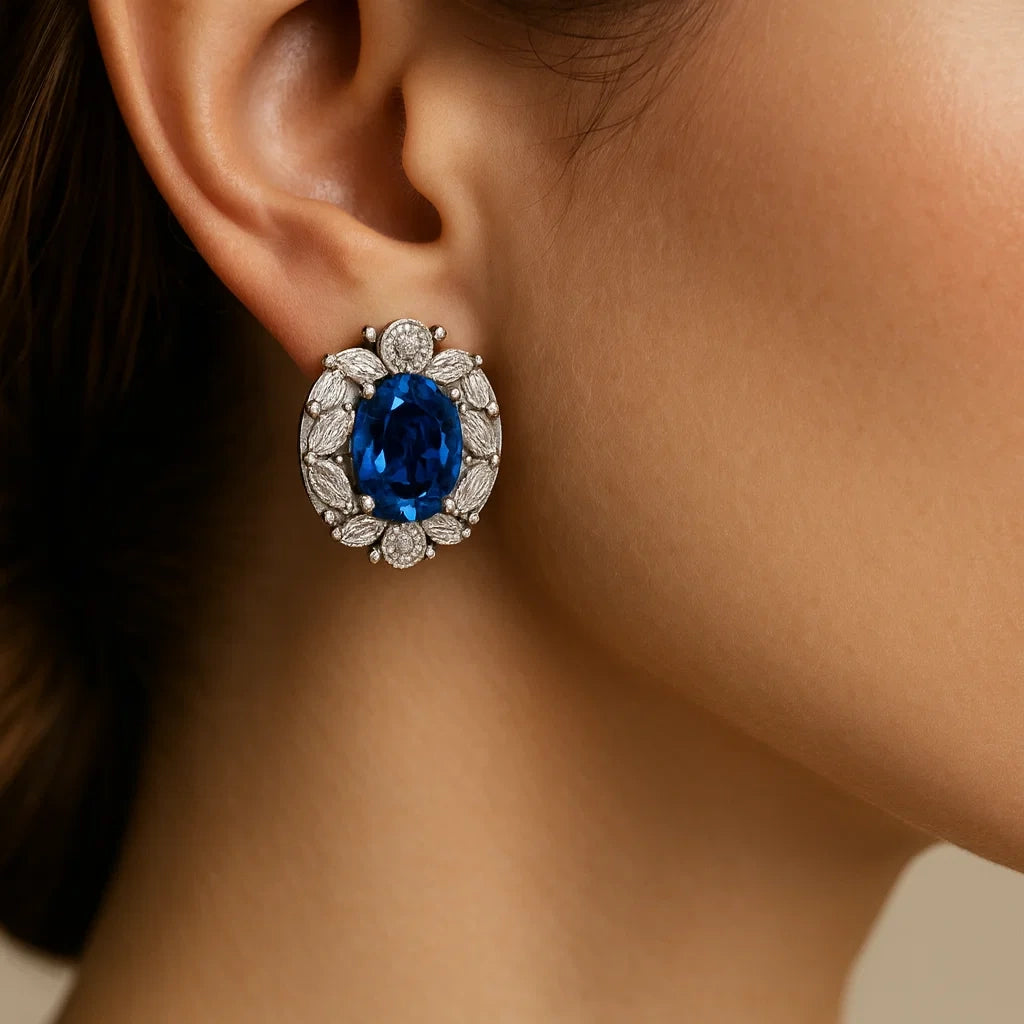 Close-up of an ear wearing a blue gemstone earring with a blurred background