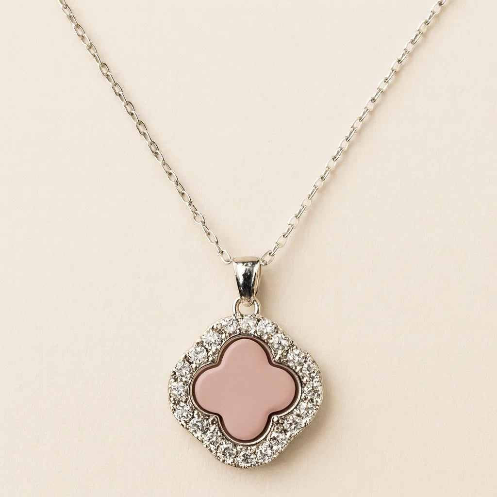Necklace with a pink clover-shaped pendant on a beige background
