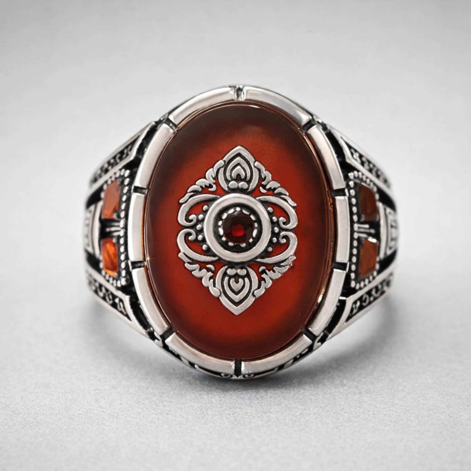 Men’s 925 sterling silver oval ring with deep red stone and raised crest emblem
