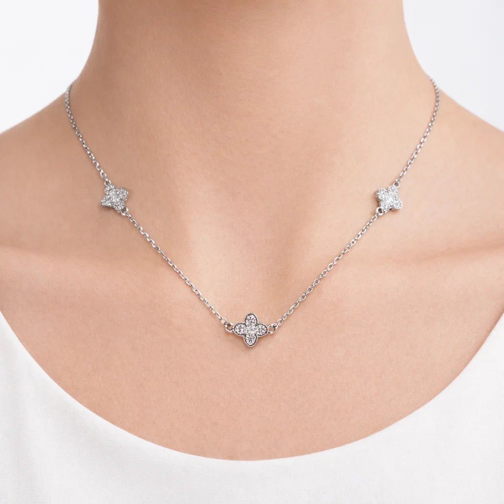 Silver necklace with star-shaped pendants on a person wearing a white top.