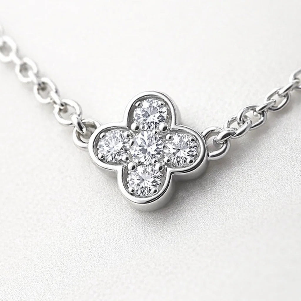 Diamond necklace with a clover-shaped pendant on a light gray background