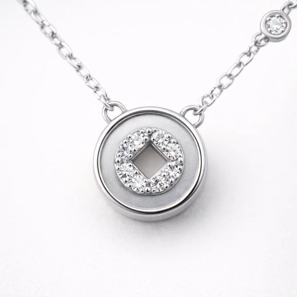 Silver necklace with a round pendant featuring a diamond design on a white background
