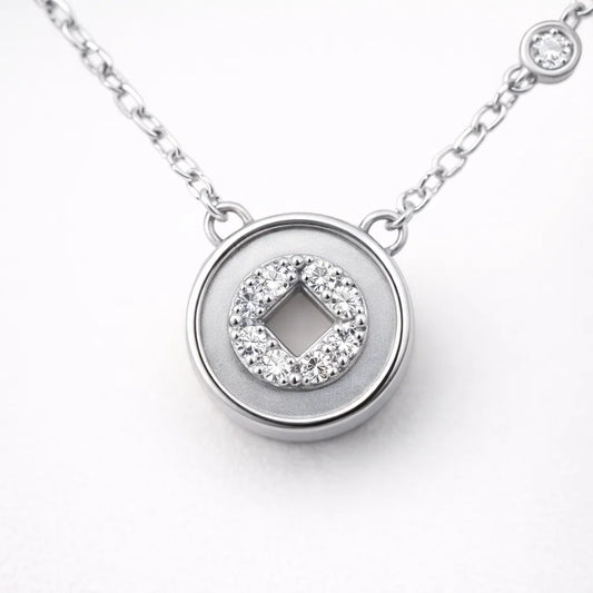 Silver necklace with a round pendant featuring a diamond design on a white background