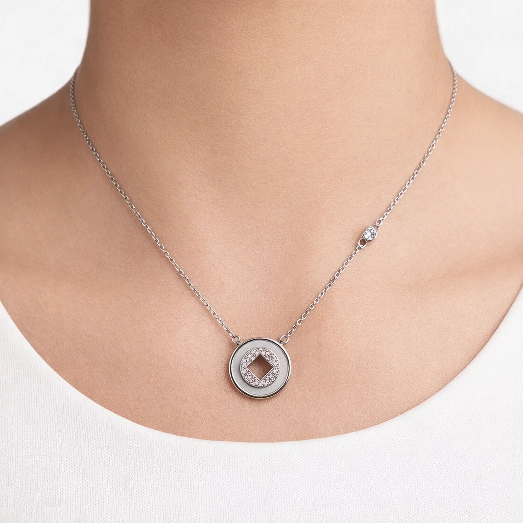 Silver necklace with a round pendant on a white background