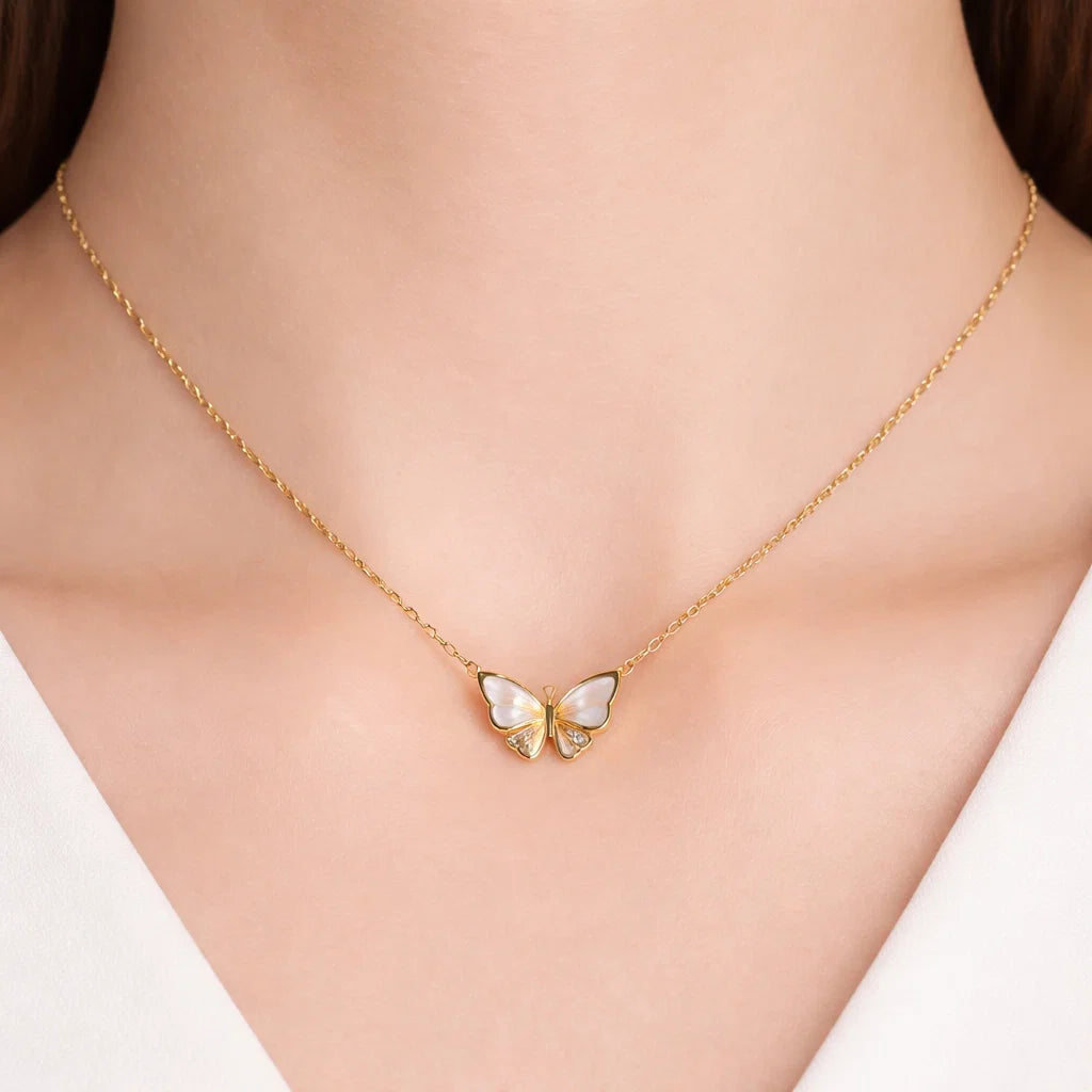 Gold butterfly necklace on a person's neck with a plain background