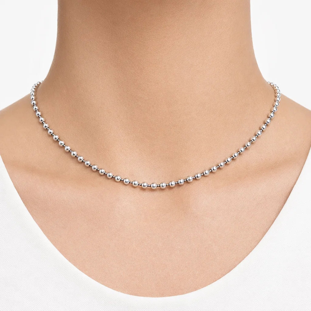 Silver beaded necklace on a person's neck against a white background