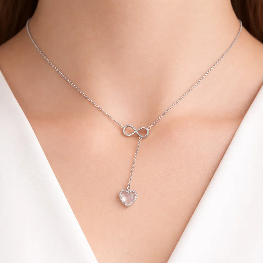 Silver necklace with a heart-shaped pendant on a person wearing a white top.