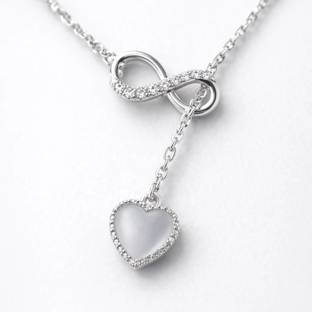 Silver necklace with an infinity symbol and heart pendant on a white background