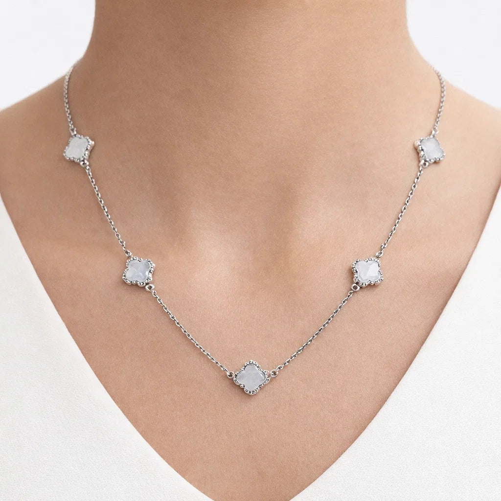 Silver necklace with square-shaped pendants on a person wearing a white top.